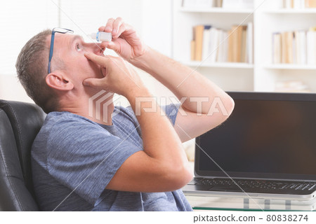 Man applying eye drops Man applying eye drops 80838274
