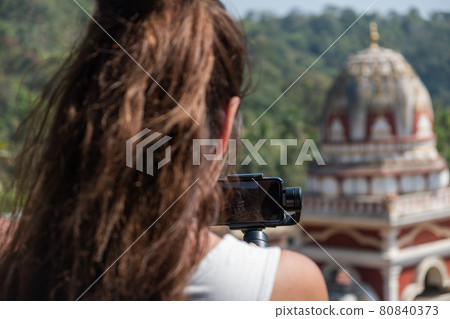 Young woman taking picture of Indian Temple Young woman taking picture of Indian Temple 80840373