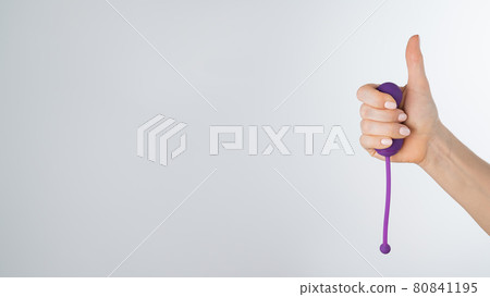 A woman recommends an electronic Kegel trainer for training pelvic floor muscles on a white background. Thumb up A woman recommends an electronic Kegel trainer for training pelvic floor muscles on a white background. Thumb up 80841195