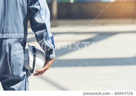 Engineer man hands holding hardhat white work helmet hard hat for Construction Engineering. Construction engineer man in safety suit hands hold white worker helmet hard hat on site City Engineering Engineer man hands holding hardhat white work helmet hard hat for Construction Engineering. Construction engineer man in safety suit hands hold white worker helmet hard hat on site City Engineering 80843729