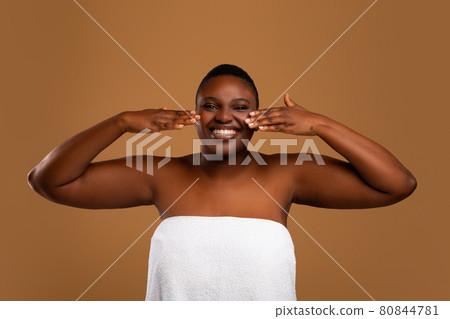 Beautiful young african american woman applying face moisturizer Beautiful young african american woman applying face moisturizer 80844781