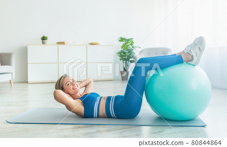 Smiling Sporty Woman Exercising With Ball At Home Smiling Sporty Woman Exercising With Ball At Home 80844864