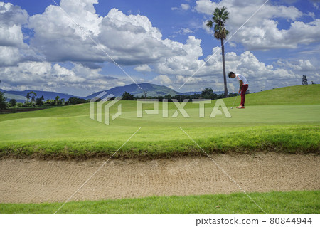 Golfers putting golf balls on the golf course in the morning. Golf man putting on green for birdie on the green golf. Golfers putting golf balls on the golf course in the morning. Golf man putting on green for birdie on the green golf. 80844944