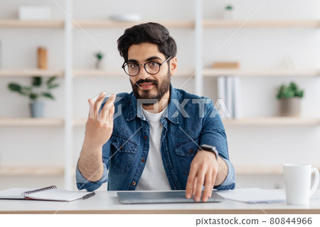 Millennial arab business coach talking and gesturing at camera, working at home office interior, free space Millennial arab business coach talking and gesturing at camera, working at home office interior, free space 80844966