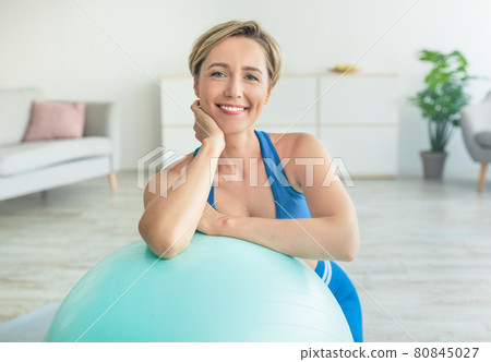 Smiling Sporty Woman Exercising Leaning On Fitness Ball At Home 80845027