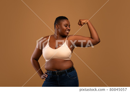 Portrait of casual young black woman showing biceps muscles Portrait of casual young black woman showing biceps muscles 80845057