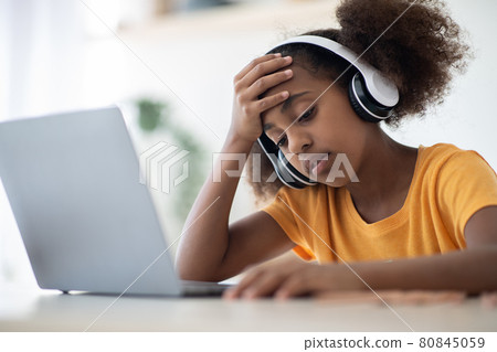 Exhausted black school girl sitting in front of laptop 80845059