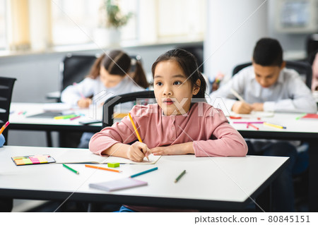 Portrait of small asian girl sitting in classroom and writing Portrait of small asian girl sitting in classroom and writing 80845151