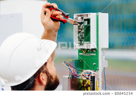 A qualified electrical engineer sets up a control and measuring device at an industrial facility on A qualified electrical engineer sets up a control and measuring device at an industrial facility on 80845234