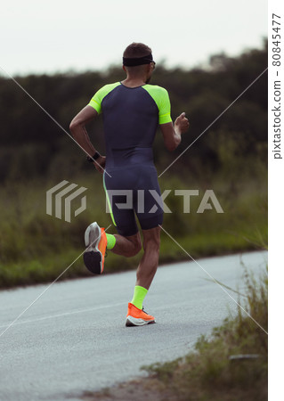 Image of young professional male triathlete, runner in motion on open road. Concept of sport, lifestyle, activity. Image of young professional male triathlete, runner in motion on open road. Concept of sport, lifestyle, activity. 80845477