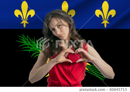 Love Guadeloupe. A girl holds a heart on her chest in her hands against the background of the flag of Guadeloupe. The concept of patriotism Love Guadeloupe. A girl holds a heart on her chest in her hands against the background of the flag of Guadeloupe. The concept of patriotism 80845713