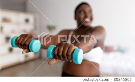 Plump black woman doing exercises with dumbbells, losing weight, strengthening her body at home, selective focus Plump black woman doing exercises with dumbbells, losing weight, strengthening her body at home, selective focus 80845865