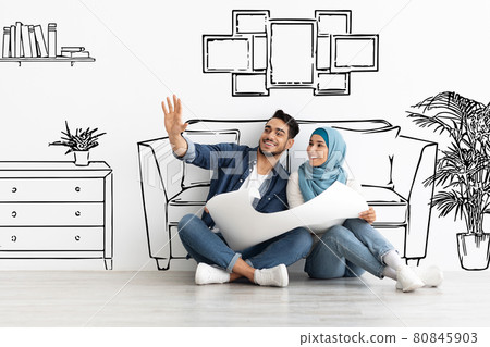 Happy arab husband and wife in hijab planning house interior 80845903