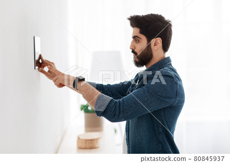 Automation domestic system. Arab man using digital tablet on wall with smart home control system app, side view Automation domestic system. Arab man using digital tablet on wall with smart home control system app, side view 80845937