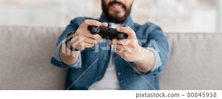 Free time. Unrecognizable guy holding gamepad playing online video game in living room, selective focus, crop, panorama Free time. Unrecognizable guy holding gamepad playing online video game in living room, selective focus, crop, panorama 80845938