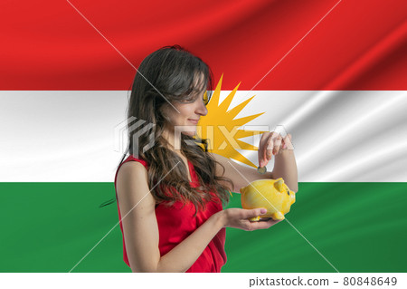 Economy in Kurdistan. Accumulating and saving money in Kurdistan. Woman putting money coin in piggy bank for saving money and plan finance Economy in Kurdistan. Accumulating and saving money in Kurdistan. Woman putting money coin in piggy bank for saving money and plan finance 80848649
