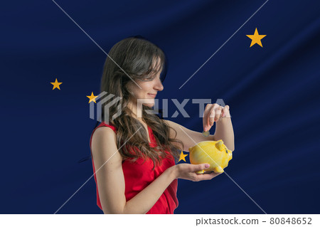 Economy in Alaska. Accumulating and saving money in Alaska. Woman putting money coin in piggy bank for saving money and plan finance Economy in Alaska. Accumulating and saving money in Alaska. Woman putting money coin in piggy bank for saving money and plan finance 80848652