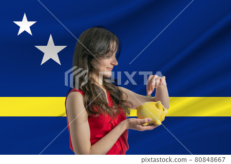 Economy in Curacao. Accumulating and saving money in Curacao. Woman putting money coin in piggy bank for saving money and plan finance Economy in Curacao. Accumulating and saving money in Curacao. Woman putting money coin in piggy bank for saving money and plan finance 80848667