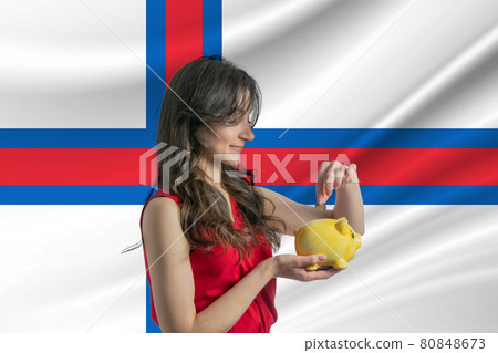 Economy in Faroe Islands. Accumulating and saving money in Faroe Islands. Woman putting money coin in piggy bank for saving money and plan finance Economy in Faroe Islands. Accumulating and saving money in Faroe Islands. Woman putting money coin in piggy bank for saving money and plan finance 80848673