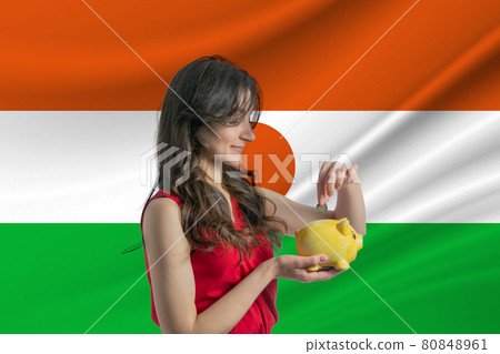Economy in Niger. Accumulating and saving money in Niger. Woman putting money coin in piggy bank for saving money and plan finance Economy in Niger. Accumulating and saving money in Niger. Woman putting money coin in piggy bank for saving money and plan finance 80848961