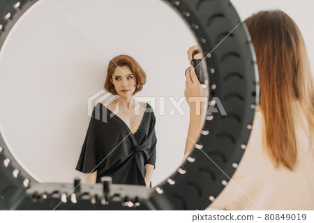 Woman photographer is taking a photo of her woman fashion model. Woman photographer is taking a photo of her woman fashion model. 80849019