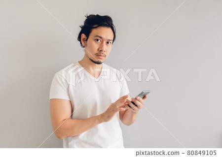 Long hair man in white casual t-shirt is using smartphone. Long hair man in white casual t-shirt is using smartphone. 80849105