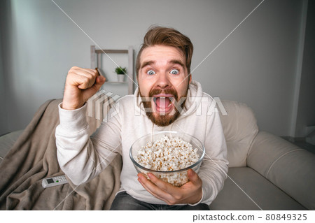 Happy guy watching TV series online. Online cinema and video streaming service concept. Happy guy watching TV series online. Online cinema and video streaming service concept. 80849325
