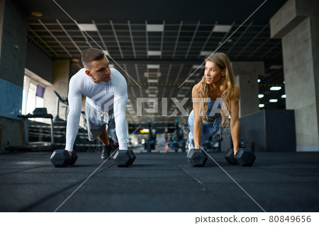 Couple doing push-ups with dumbbells in gym 80849656