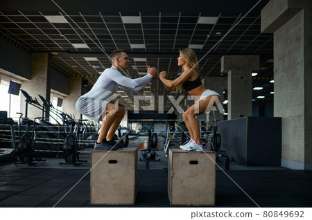 Slim couple doing balance exercise on cubes in gym 80849692