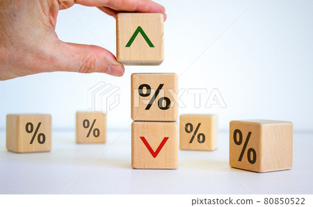 Interest rates symbol. Wooden cubes, businessman changed the direction of an arrow symbolizing that the interest rates are going down or up. Beautiful white background. Business concept. Copy space. 80850522