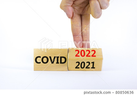 Symbol of covid-19 pandemic in 2022. Doctor turns a wooden cube and changes words 'covid 2021' to 'covid 2022'. Beautiful white background, copy space. Medical, covid-19 pandemic in 2022 concept. 80850636