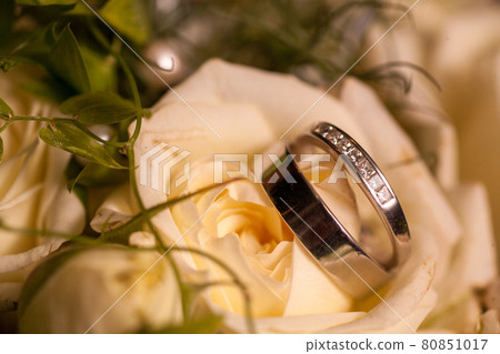 Close view on white rose flowers with wedding rings in warm colors and a romantic setting 80851017