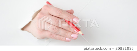 Female hand holds red pencil in hole made of white paper 80851053
