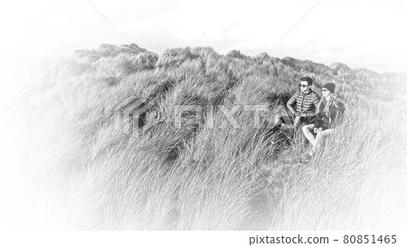 Young couple enjoy the sunset while sitting on a grassy hill Young couple enjoy the sunset while sitting on a grassy hill 80851465