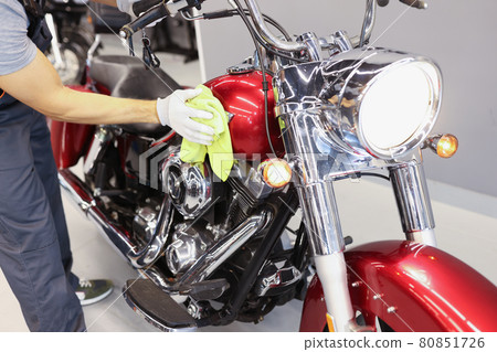 Man cleaning motorcycle in service center closeup 80851726