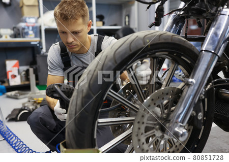 Man checks tire pressure on motorcycle in workshop 80851728
