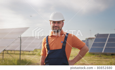 Portrait ecology worker in hard hat standing at solar panel field. Industrial people. Portrait of male engineer in hard helmet turning head and looking to camera. Concept of solar station development 80852880