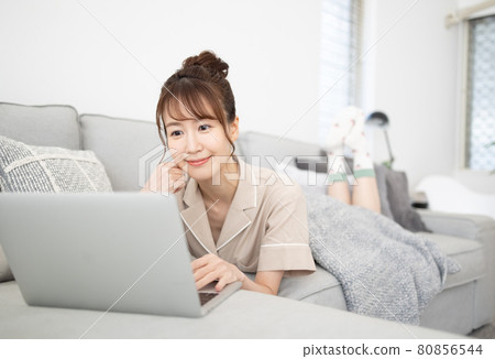 一個微笑的女人看著沙發上的電腦 一個微笑的女人看著沙發上的電腦 80856544