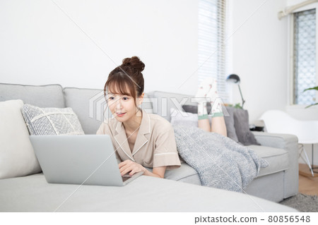 一個微笑的女人看著沙發上的電腦 一個微笑的女人看著沙發上的電腦 80856548