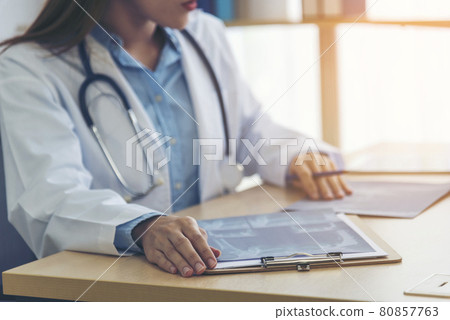 Two asian women doctors discuss meeting doctor's office medical clinic looking x-ray film consulting patient disease. Asian medical lab young women talking together discussing healthcare teamwork 80857763