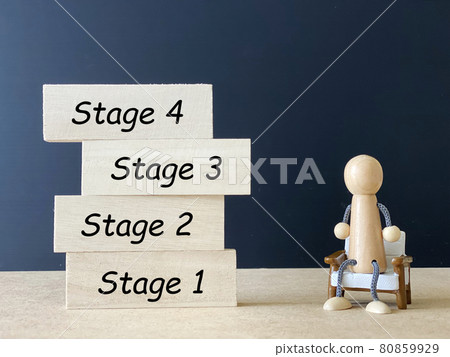 Four stacked wooden boards and a doll sitting on a chair_stage with letters Four stacked wooden boards and a doll sitting on a chair_stage with letters 80859929