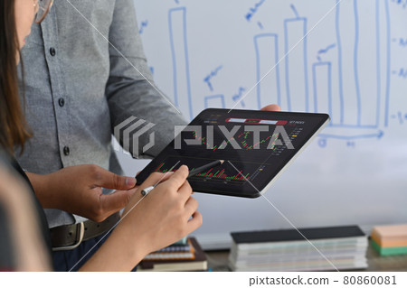 Two businesspeople analyzing stock market investment strategy together in meeting room. 80860081