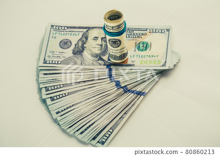 A coiled 100 dollar bill which rests on another angled 100 dollar bill isolated on white background 80860213