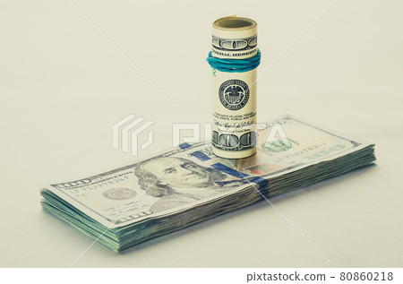 A coiled 100 dollar bill which rests on another angled 100 dollar bill isolated on white background A coiled 100 dollar bill which rests on another angled 100 dollar bill isolated on white background 80860218
