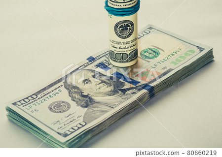 A coiled 100 dollar bill which rests on another angled 100 dollar bill isolated on white background A coiled 100 dollar bill which rests on another angled 100 dollar bill isolated on white background 80860219