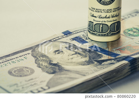 A coiled 100 dollar bill which rests on another angled 100 dollar bill isolated on white background A coiled 100 dollar bill which rests on another angled 100 dollar bill isolated on white background 80860220