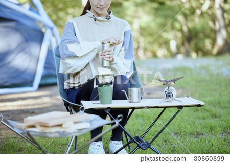 A woman preparing to brew coffee at a campsite. A woman preparing to brew coffee at a campsite. 80860899