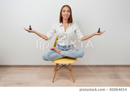 Beautiful woman in casual clothes sitting on a chair holding bottles of nail varnish over white background 80864654