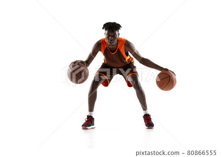 Young african man, basketball player in motion with two balls isolated over white studio background. Front view 80866555