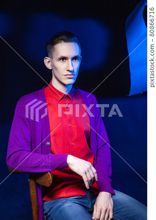 Stylish man in red shirt in dark studio Stylish man in red shirt in dark studio 80866716